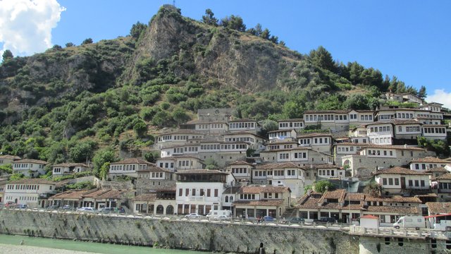 De witte Ottomaanse huizen van de wijk Mangalem in Berat tegen de burchtheuvel, boven de rivier Osum