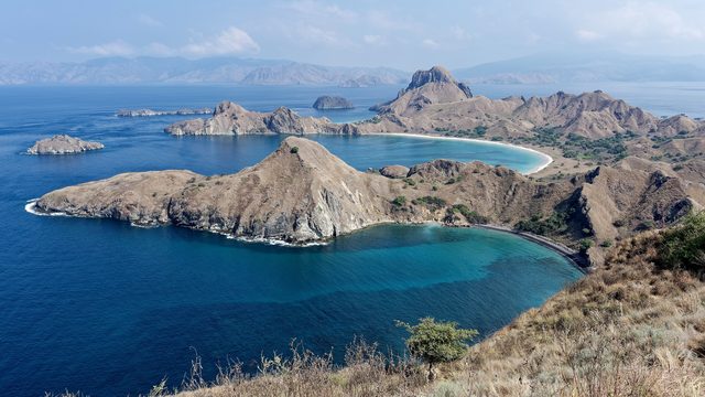 Uitzicht vanaf de top van Padar over drie baaien met turquoise water en droge heuvels in het Nationaal Park Komodo